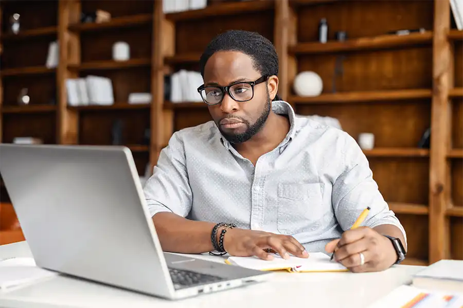 man writing on notebook and working using laptop in modern style office